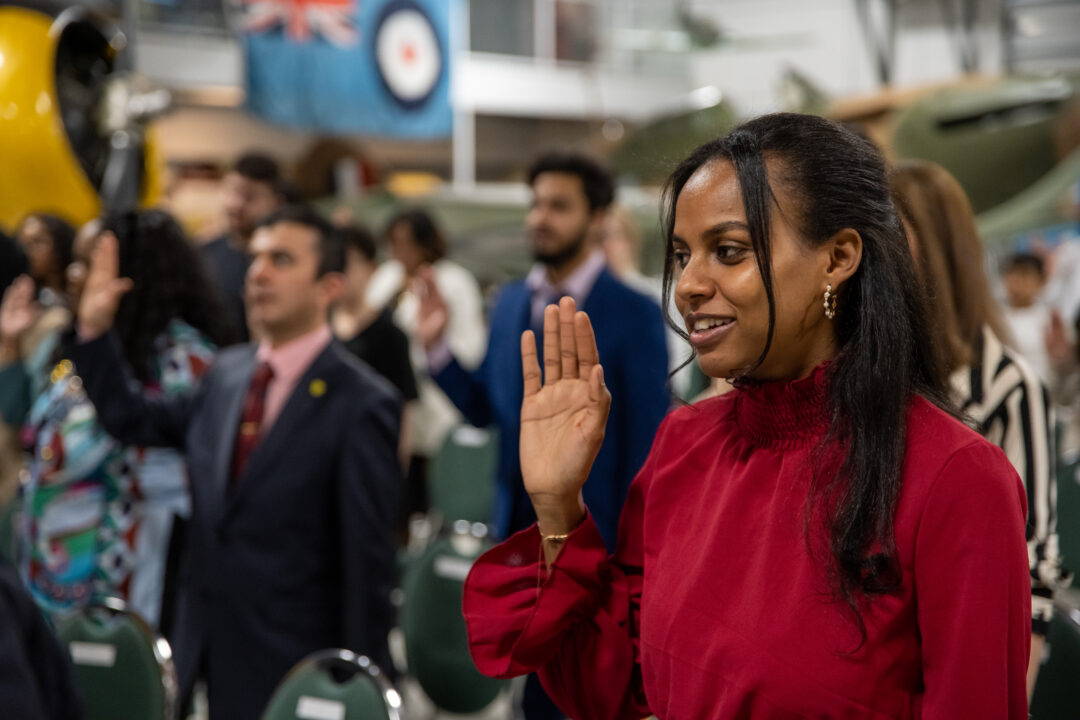 Group of people raising their hand to take an oath at a Citizenship Ceremony.