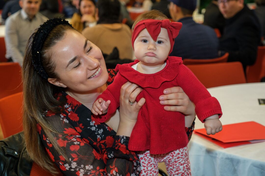 Woman and baby dressed in red at citizenship ceremony.