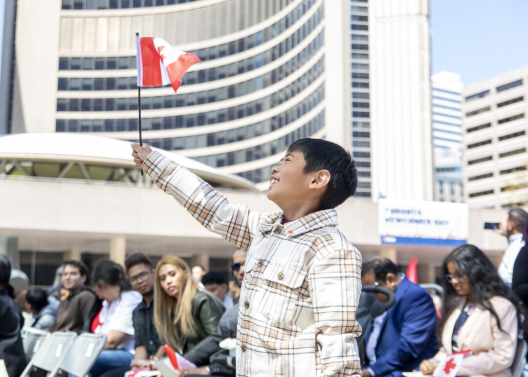 Child with little Canadian flag in front of Toronto City Hall
