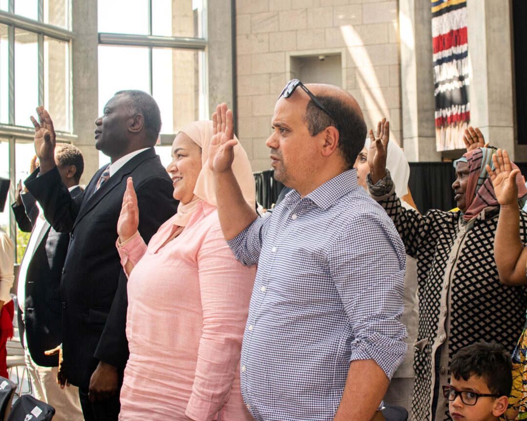 Photo of people with their right hands up taking their oath of citizenship.