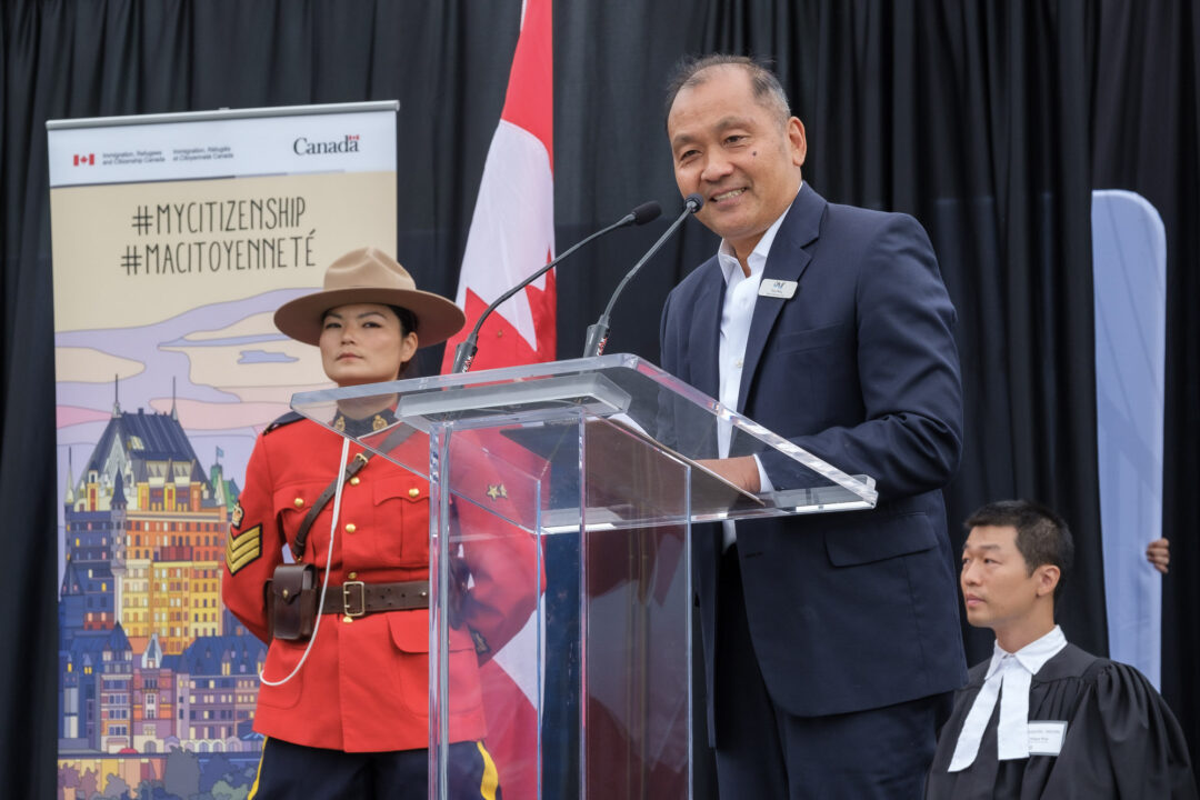 Peter Wong speaking at a Canadian Citizenship ceremony in front of a clear podium.